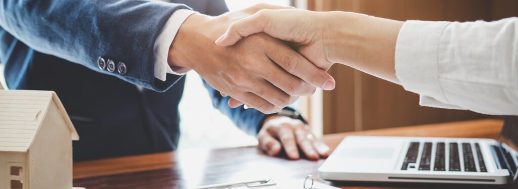 Real estate agent and customers shaking hands together celebrating finished contract